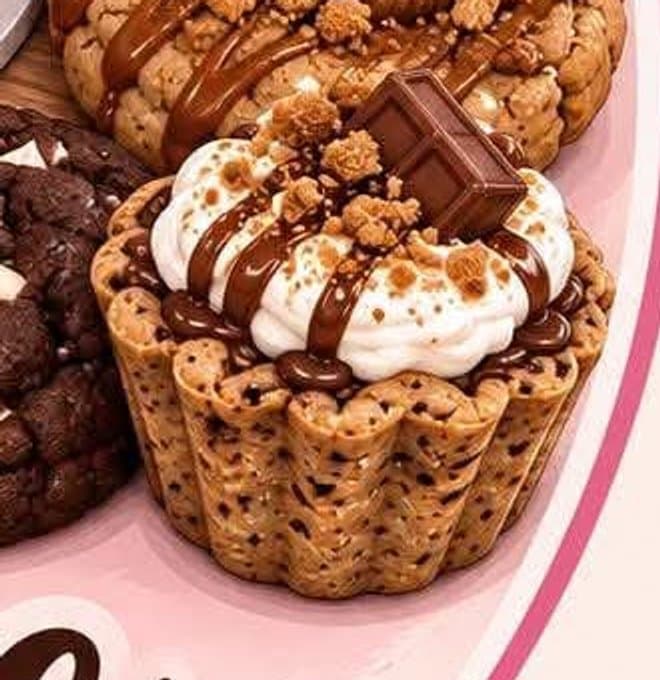 A stuffed cookie cup topped with cream and a chocolate drizzle